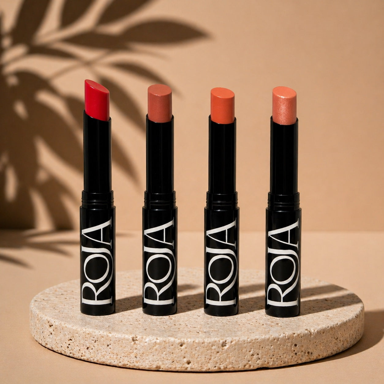 4 Shade Bloom Balm Roja Beauty tinted lip balm with different shades on a beige background, featuring the ROJA brand.